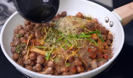 Tempering boiled chole with ghee and spices for samosa chaat