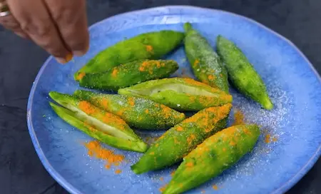 Fresh karelas being washed, peeled, slit, and rubbed with salt and turmeric for Soya Kheema Karela Recipe