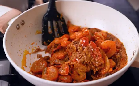 Adding prawns and smoking the biryani for flavor.